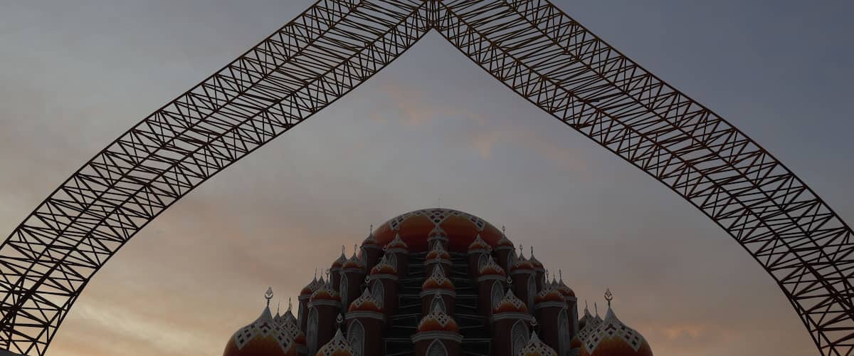 A large arch structure framing a domed building with intricate patterns.