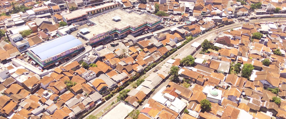 An aerial view of a densely packed urban area with numerous buildings, a prominent train station, and a large open plaza.