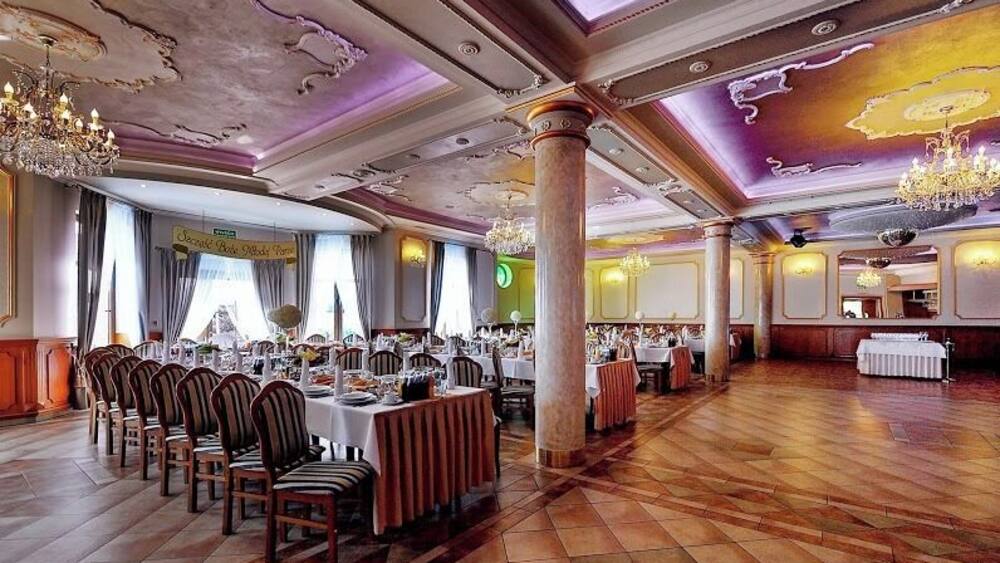 Une salle de banquet dotée de parquets en bois, de tables rondes et de chaises.