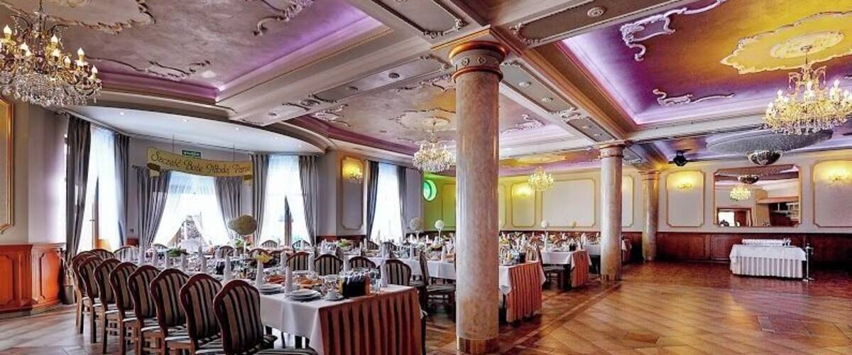 A banquet hall with wooden floors, round tables, and chairs.