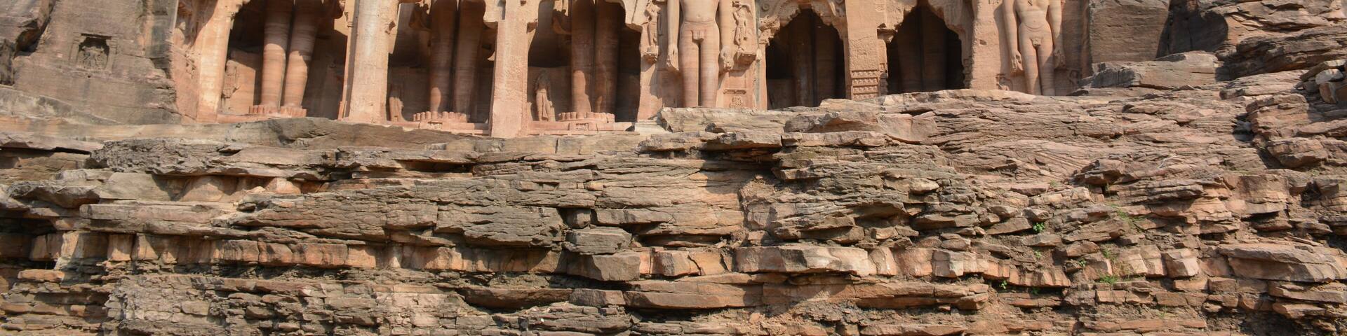 A rock-cut temple with multiple statues and intricate carvings.
