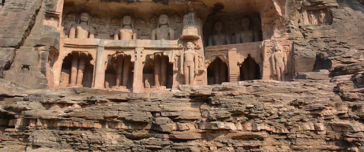A rock-cut temple with multiple statues and intricate carvings.