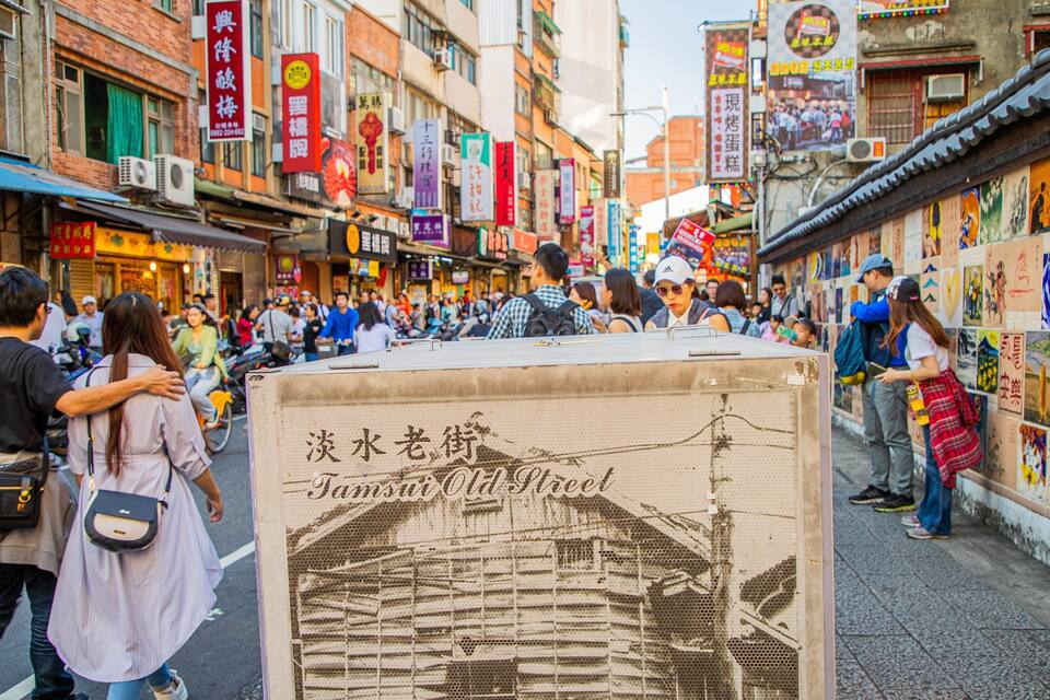 A crowded street with traditional buildings and colorful signs.