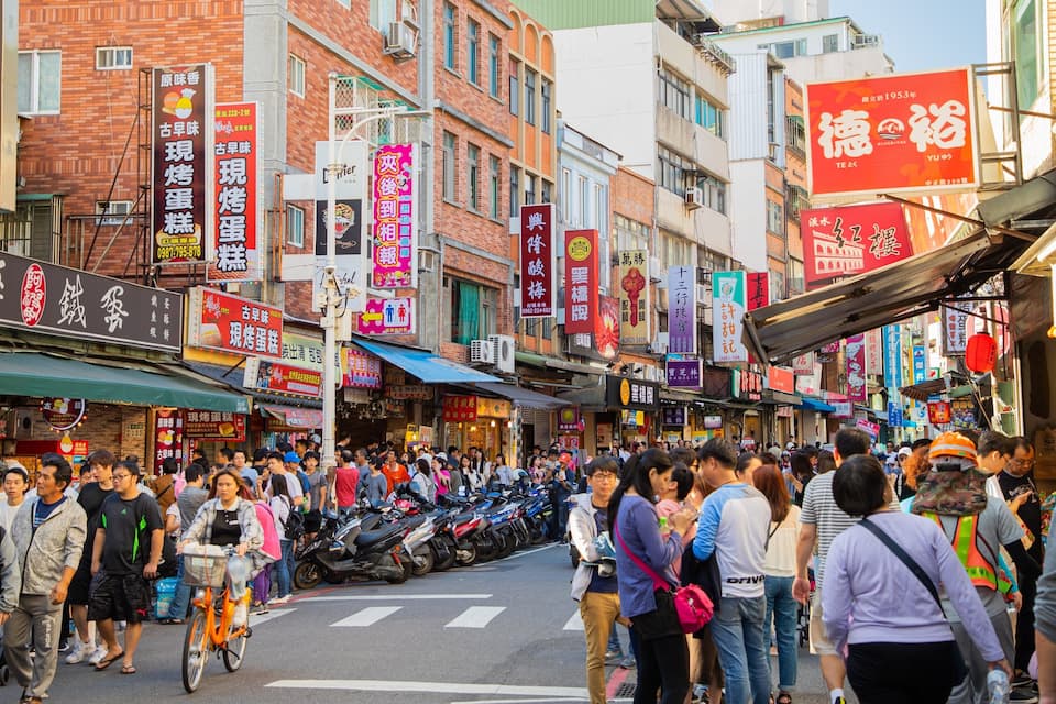 A crowded street with many people and motorcycles.