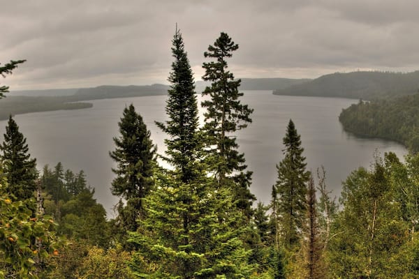 Un lac entouré d’une forêt dense et de montagnes.