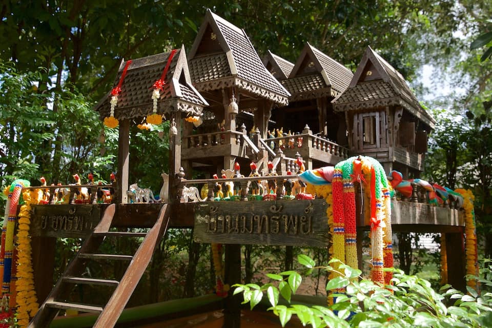 A traditional wooden structure with multiple levels, adorned with colorful garlands and statues.