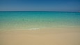 A beach with clear turquoise water and sandy shore.