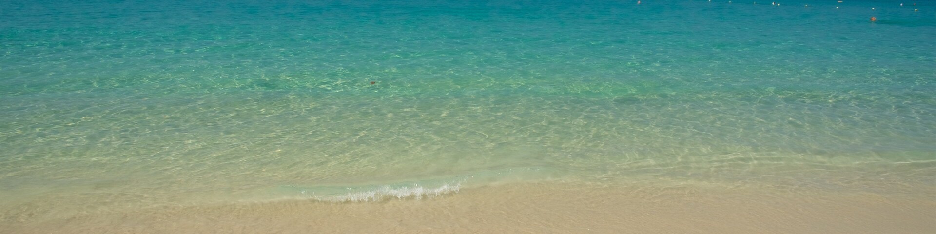 Uma praia com águas turquesa cristalinas e areal arenoso.
