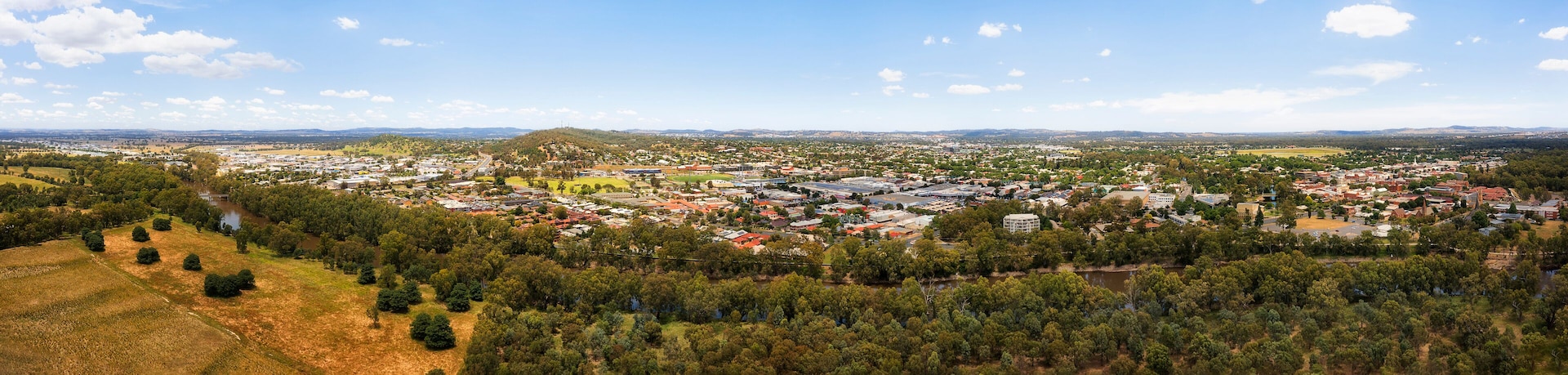 A town with a central hill, surrounded by dense forests and a river.