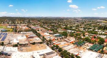 Vista panorámica de una ciudad con río, zonas verdes y una extensa área industrial con paneles solares.