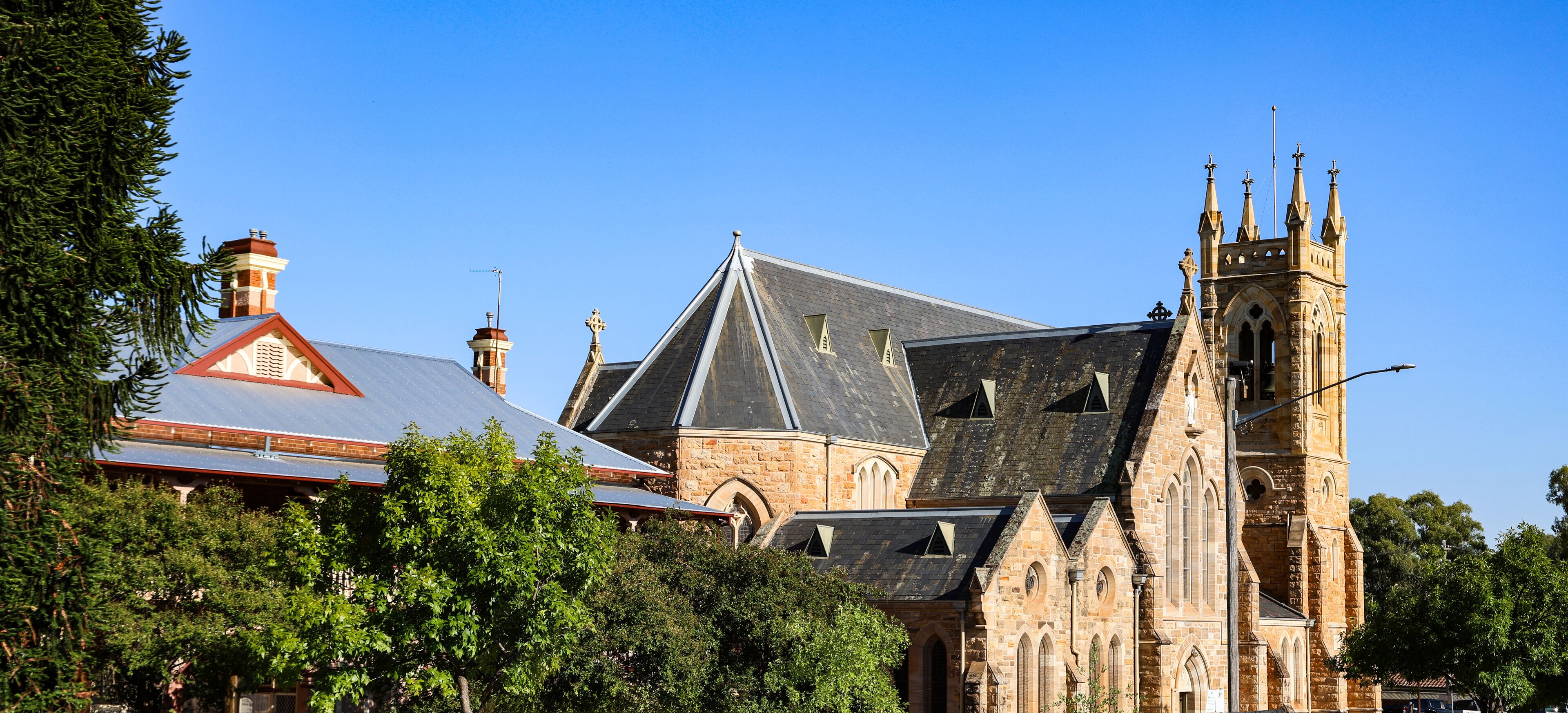 A historic church with a prominent tower and a red-roofed building with solar panels.