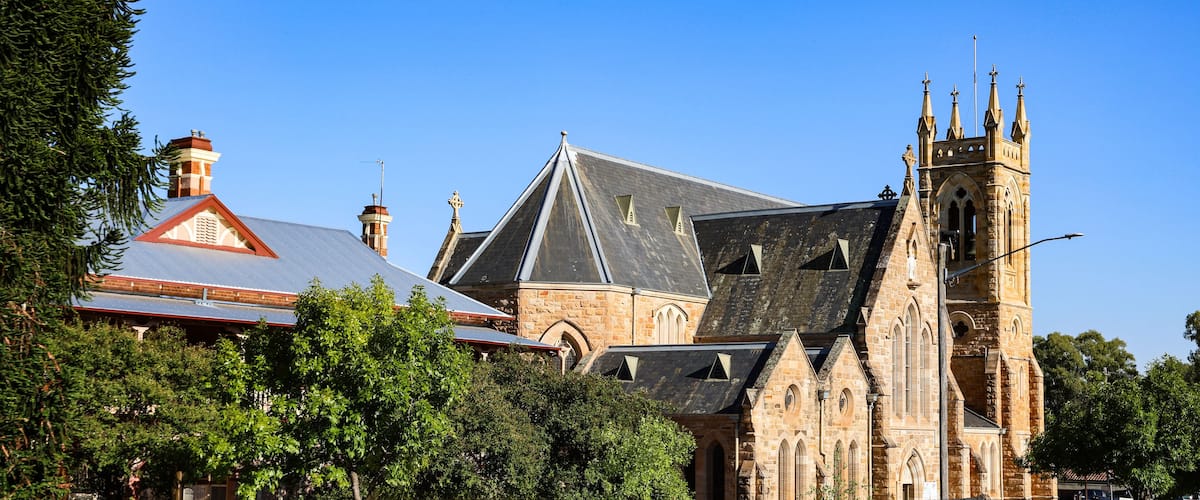 A historic church with a prominent tower and a red-roofed building with solar panels.