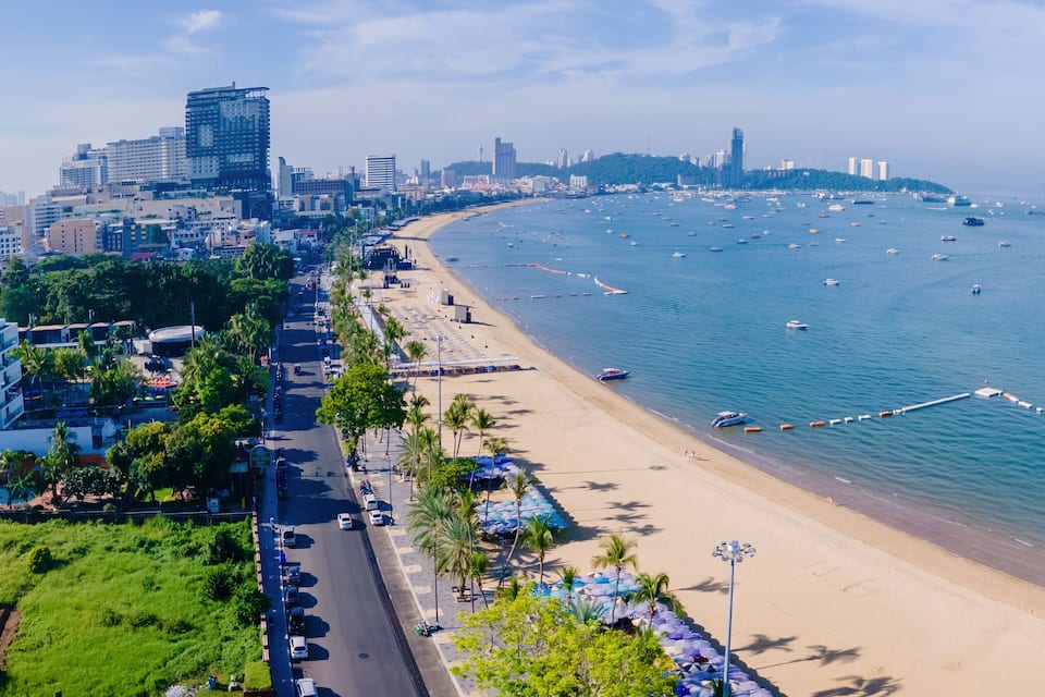 A coastal cityscape with a beach, boats, and high-rise buildings.