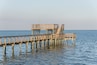 Wooden fishing piers stretching out over Galveston Bay in Kemah, Texas, USA. Foot pier for saltwater fishing of vacation home/beach house rental/bay home in Lighthouse District waterfront at sunset