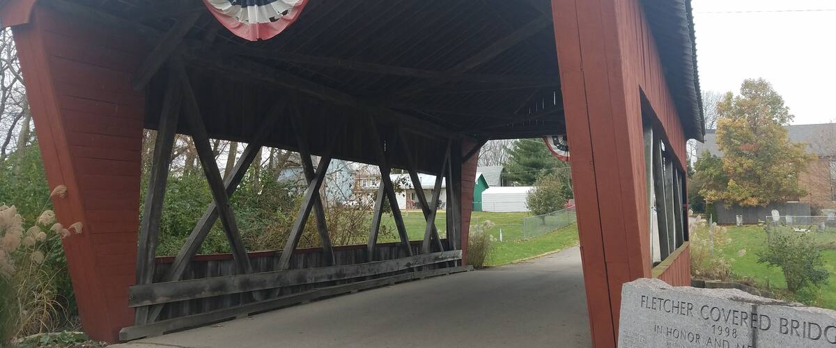 A covered bridge with a sign that reads "Fletcher 1998 Smith Truss Bridge".