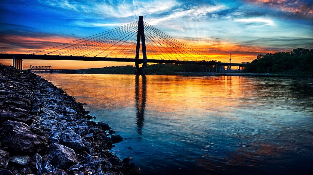 Un puente colgante al atardecer, con una costa rocosa.