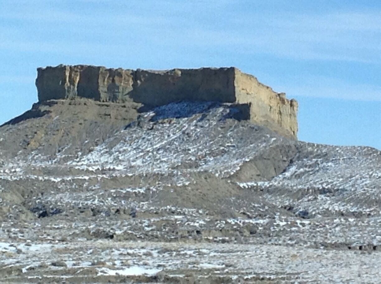 A snow-covered mountain with a flat-topped peak and a rocky base.