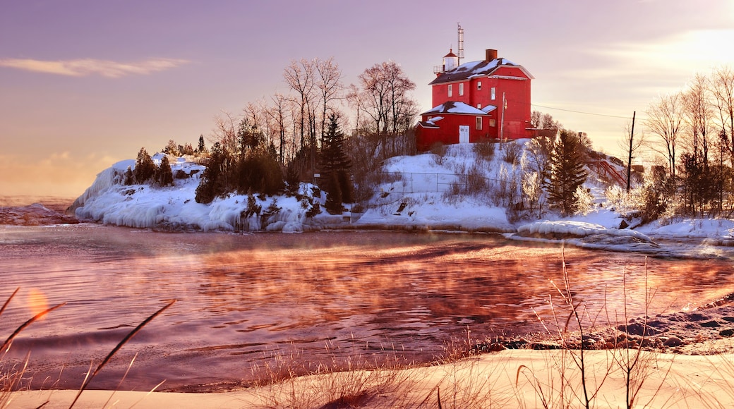A red building on a snowy island with a frozen river in the foreground.
