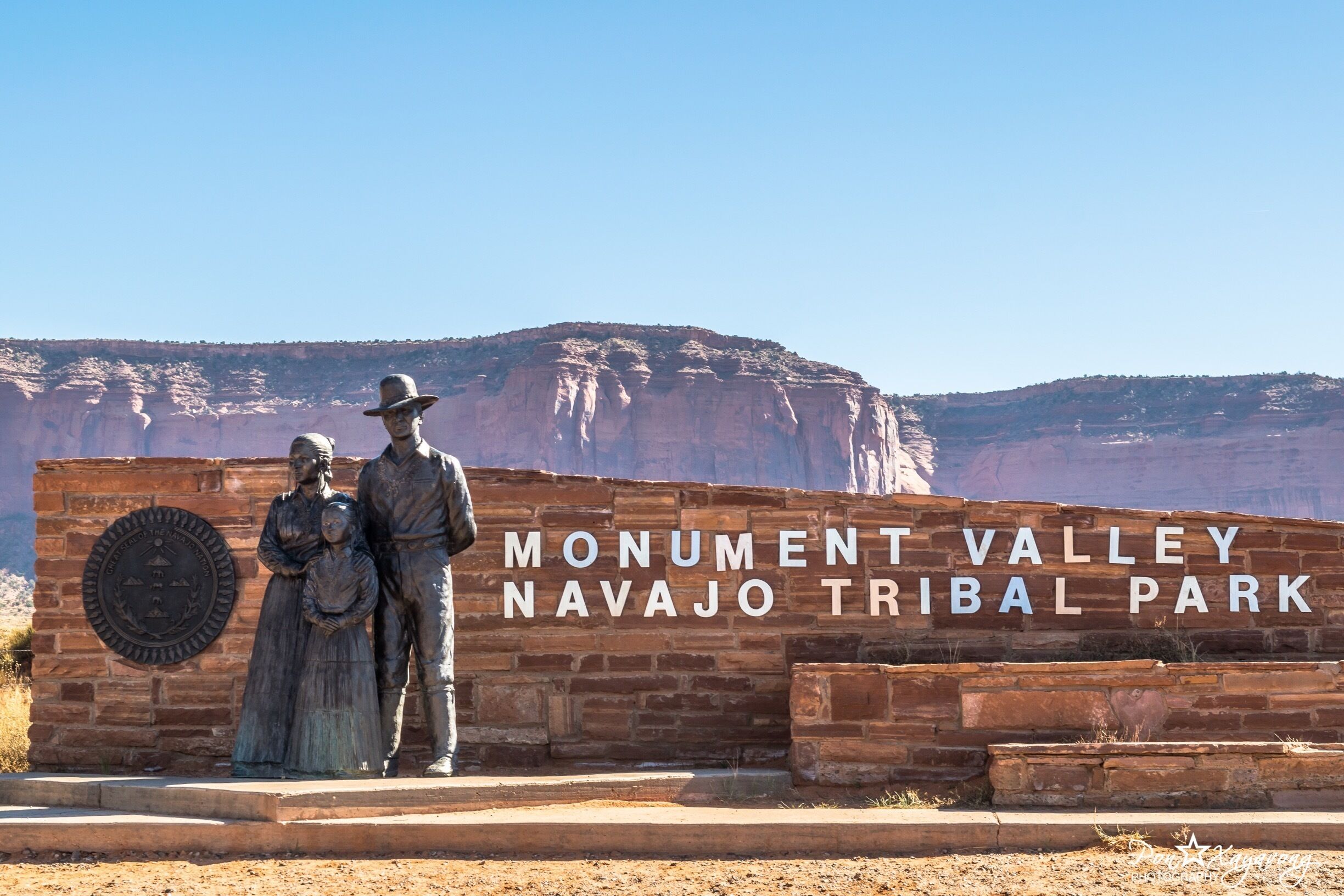 Placa do Parque Tribal Navajo do Vale dos Monumentos com uma estátua de um homem e uma mulher.
