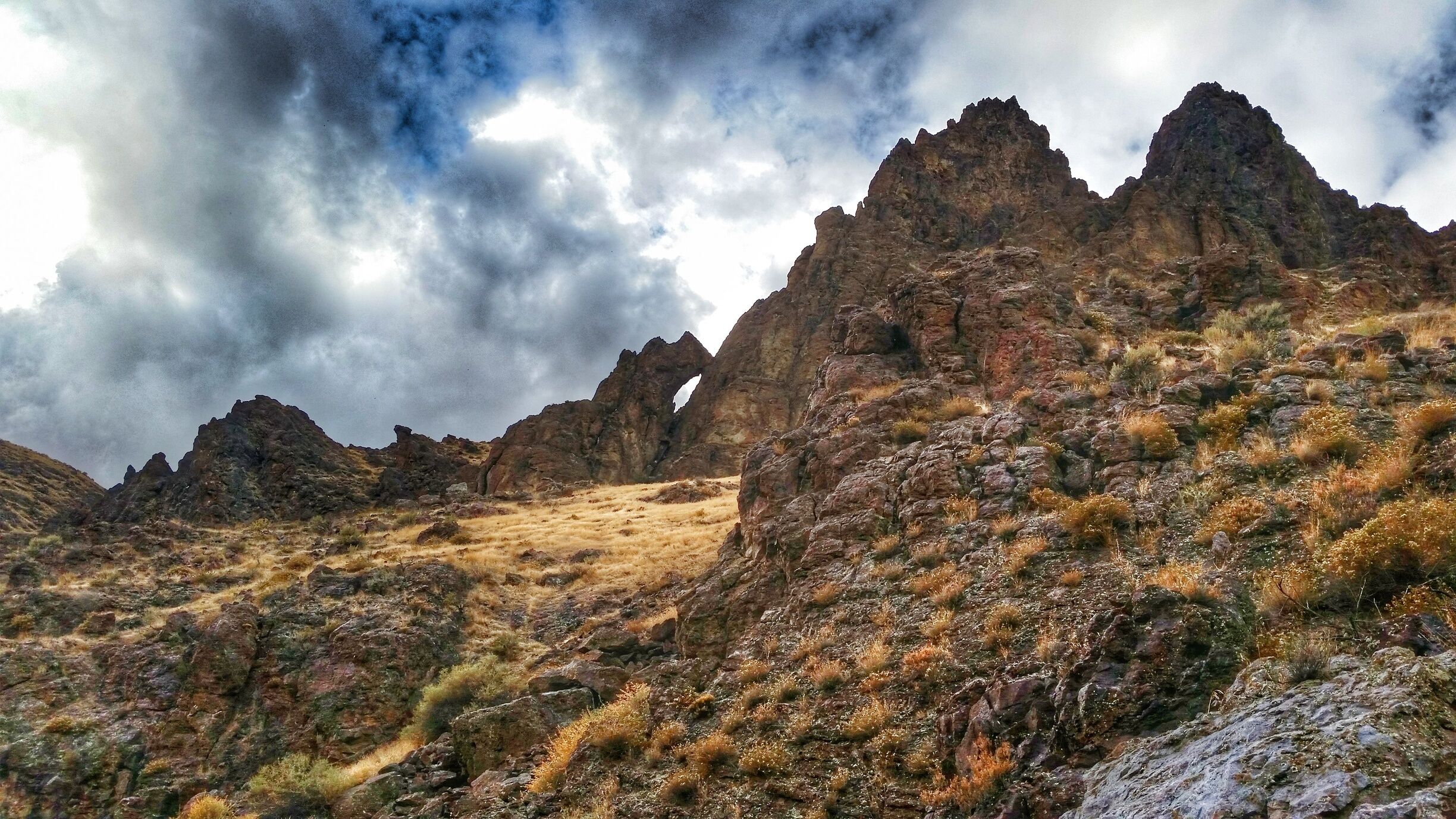 Rugged mountains with sparse vegetation and a dramatic sky.
