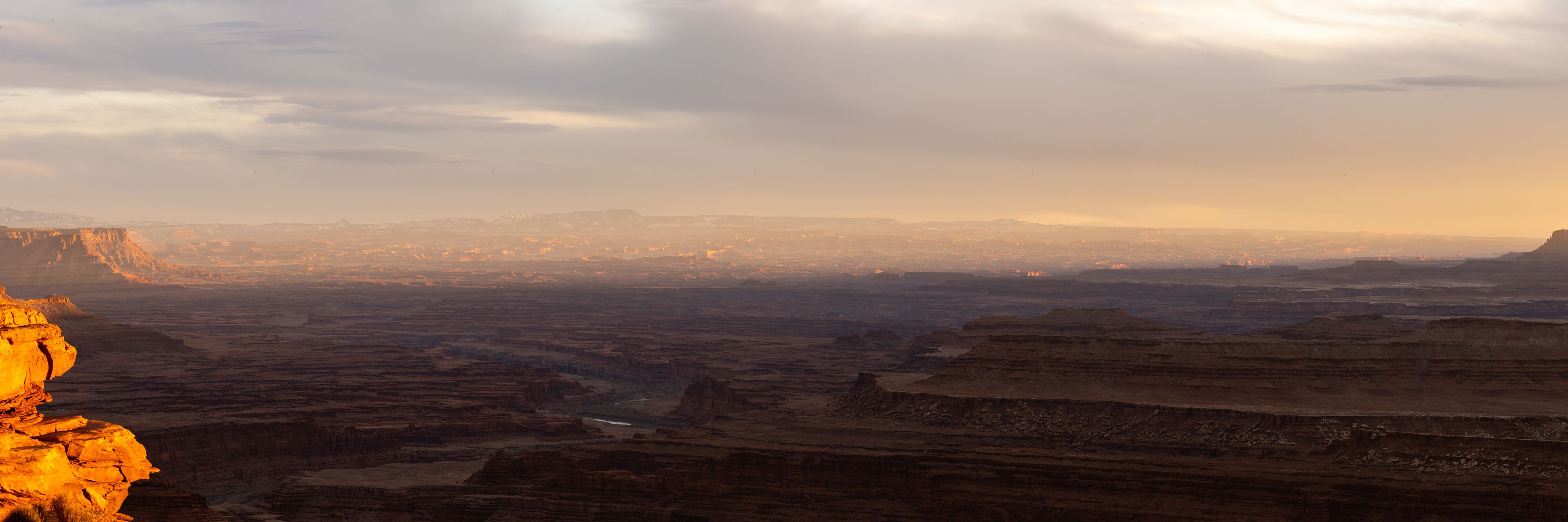 A canyon landscape with layered rock formations and a distant city skyline.