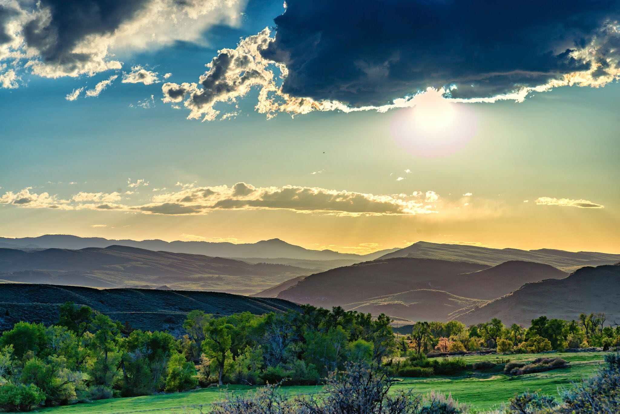 A mountainous landscape with a clear sky and the sun setting or rising.