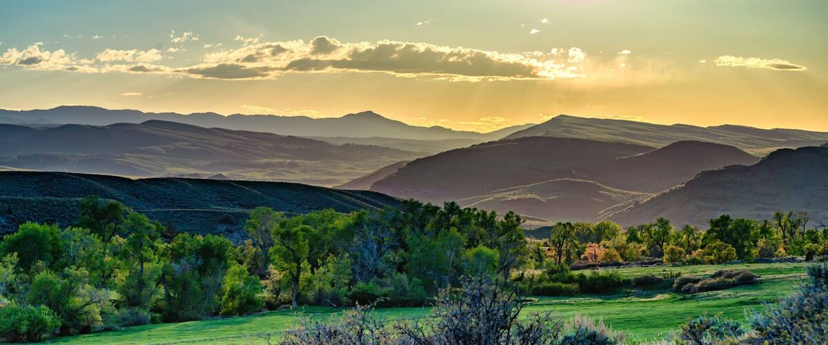 A mountainous landscape with a clear sky and the sun setting or rising.