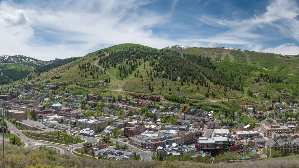 A town nestled in a valley with a backdrop of green hills and a mountain range.