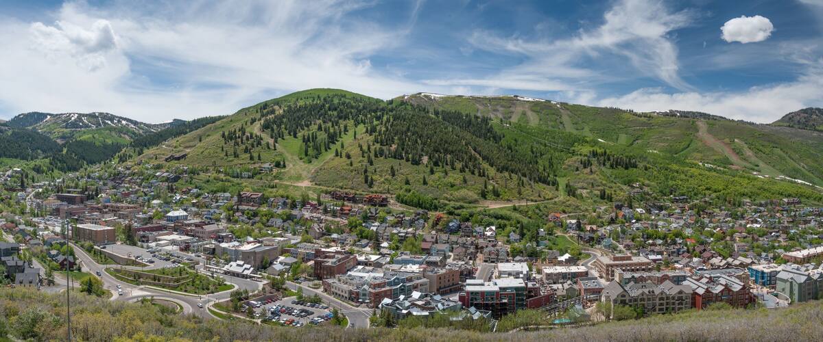 A town nestled in a valley with a backdrop of green hills and a mountain range.