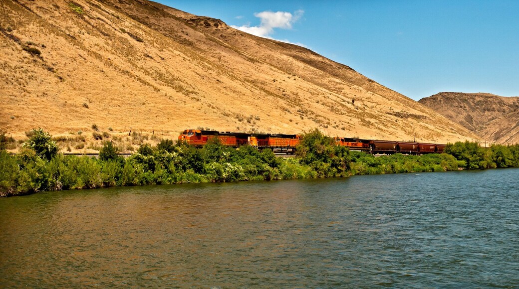 Yakima River Canyon scenic drive in a horizontal panorama showing the river, the canyon walls and the blue sky.