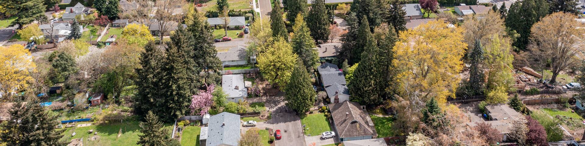 Aerial drone view of Milwaukie, OR, showcasing residential neighborhoods, tree-lined streets, and urban landscape along the Willamette River, with views of parks, commercial areas, and suburban homes