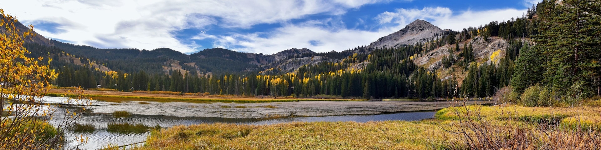 Silver Lake by Solitude and Brighton Ski resort in Big Cottonwood Canyon. Panoramic Views from the hiking and boardwalk trails of the surrounding mountains, aspen and pine trees in brilliant fall autu