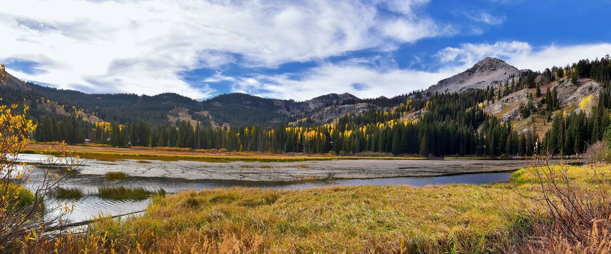 A mountainous landscape with a lake, autumn-colored trees, and a clear sky.
