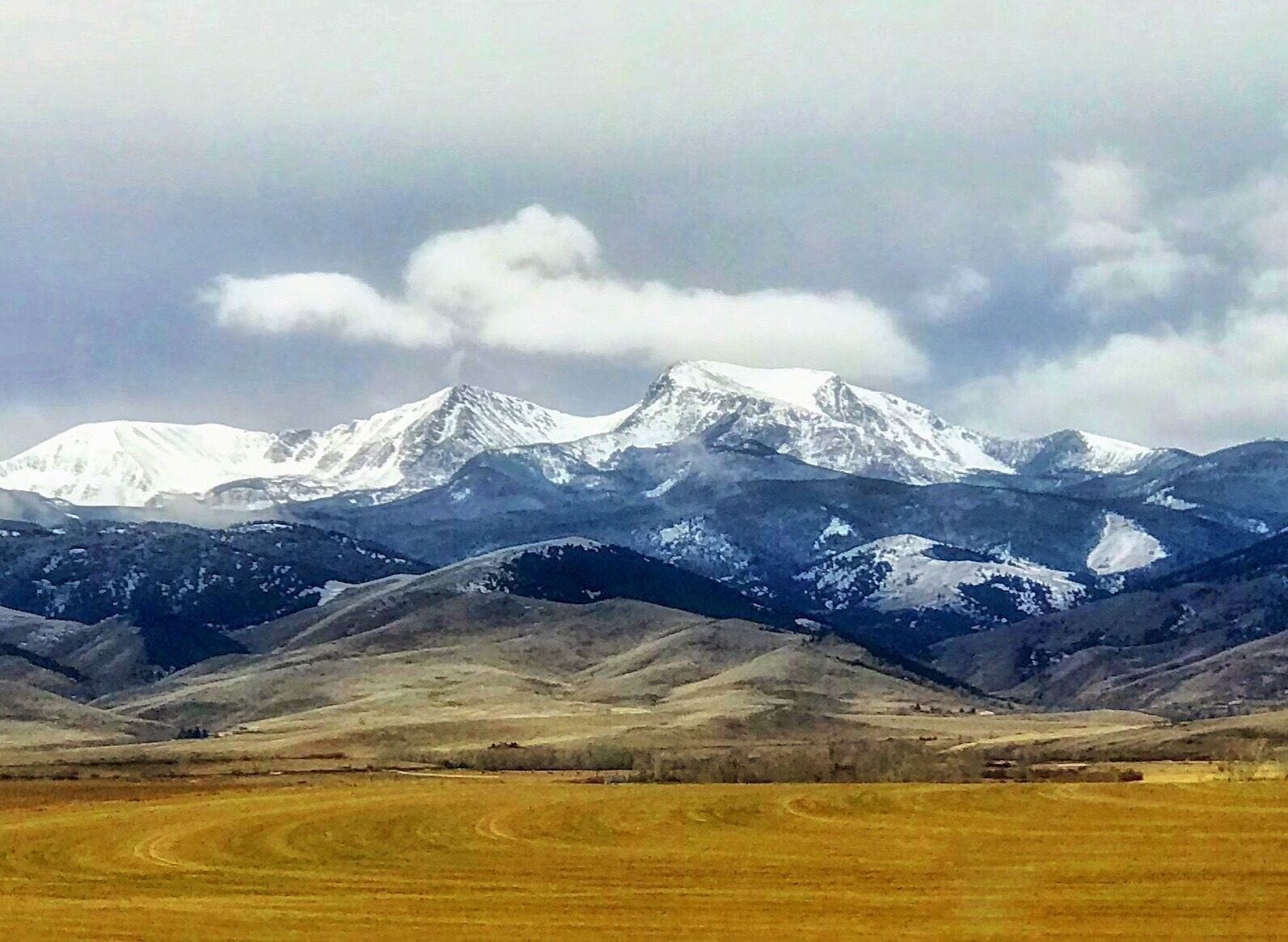 A snow-capped mountain range with a valley in the foreground.