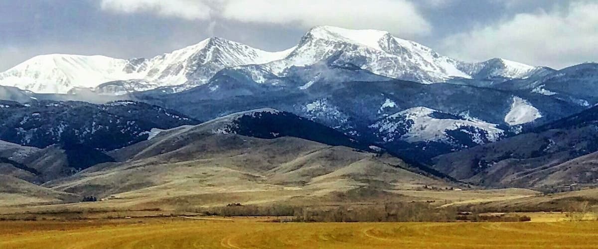 A snow-capped mountain range with a valley in the foreground.