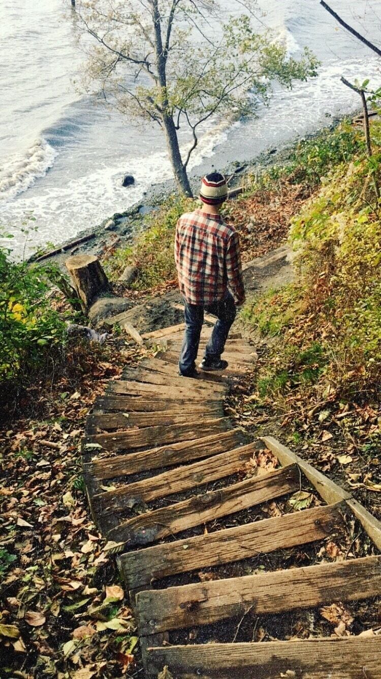 A person walking on a wooden boardwalk beside a body of water.