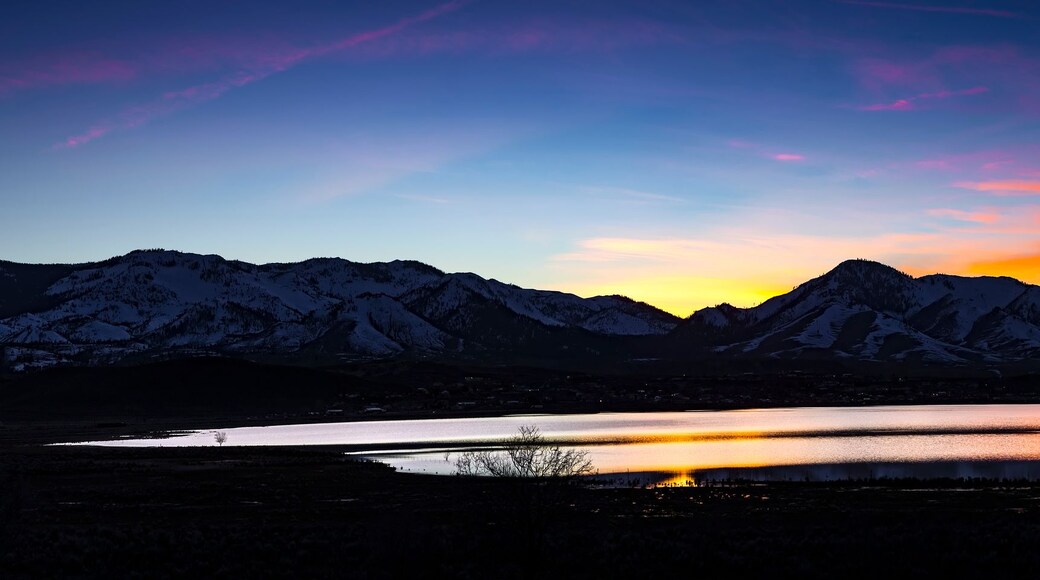 Ein Bergmassiv bei Sonnenuntergang mit einem See im Vordergrund.