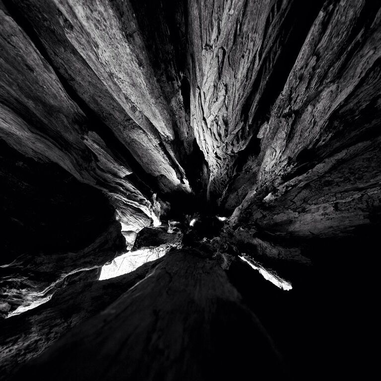A black and white view of a rock formation with layered strata converging towards a central point.
