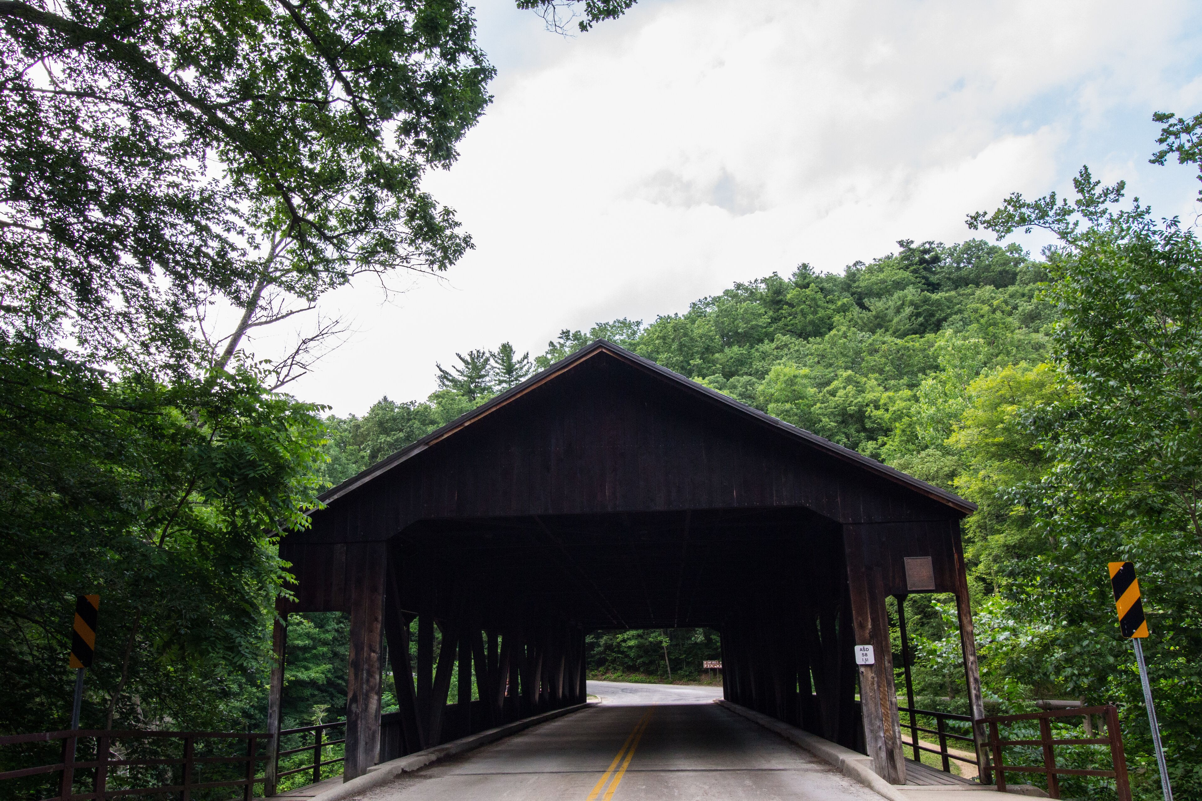 A covered wooden bridge surrounded by lush green trees.