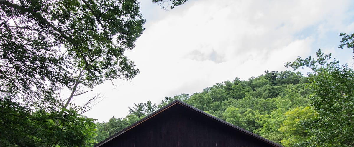 A covered wooden bridge surrounded by lush green trees.