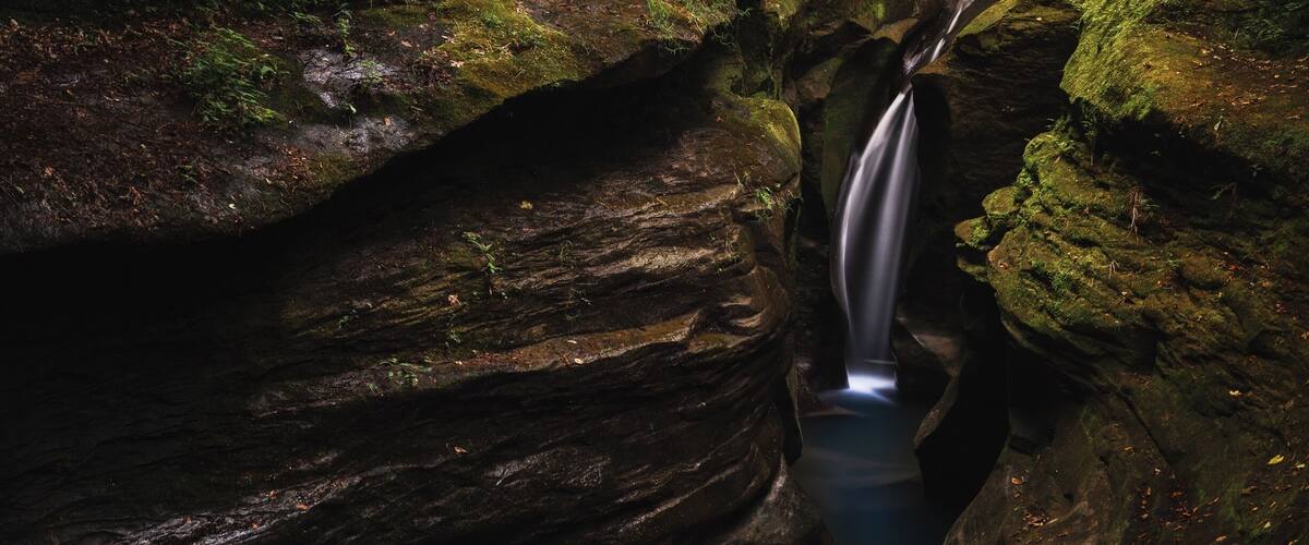 A waterfall cascading down a moss-covered rock formation.