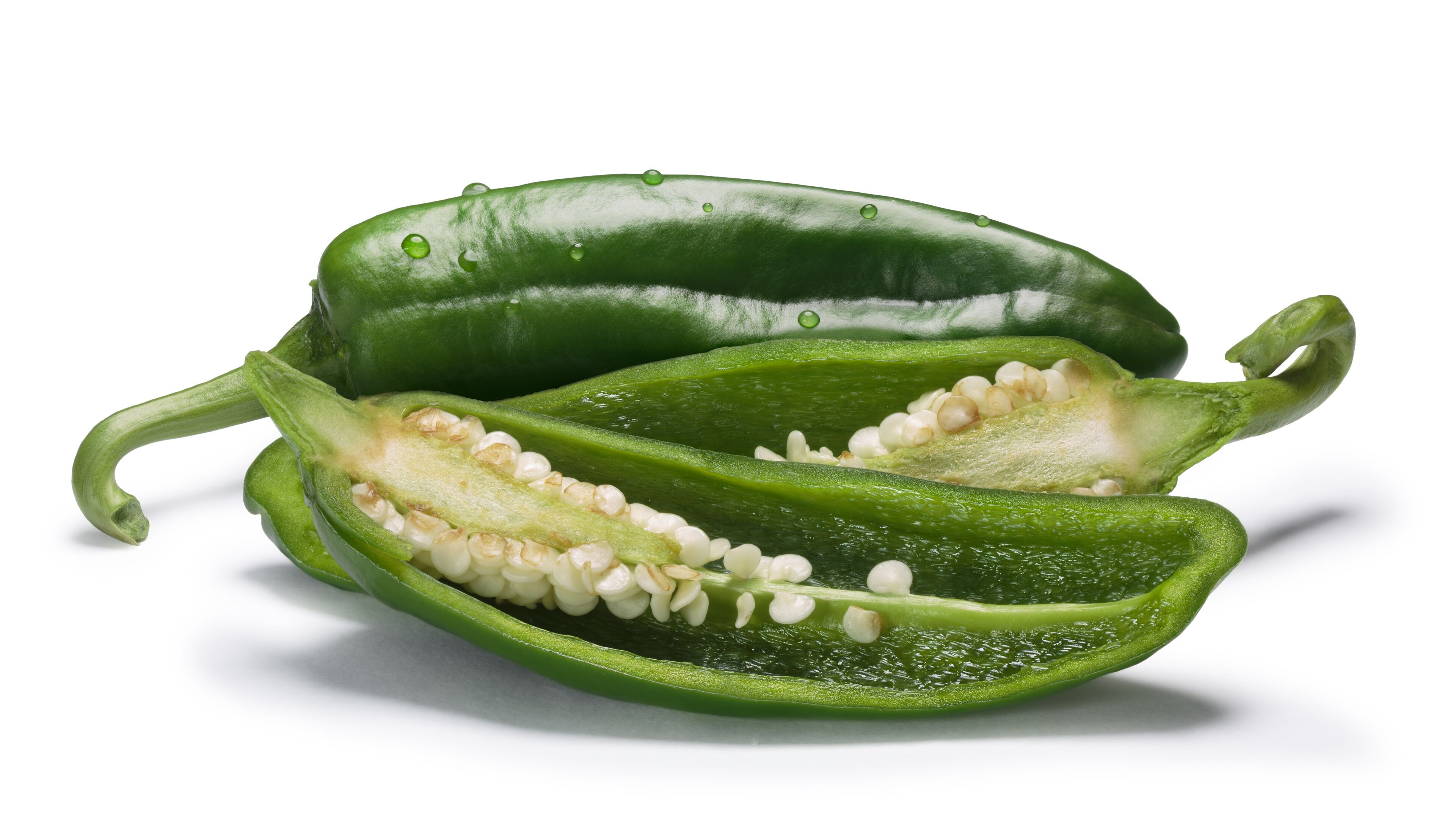 A green bell pepper cut in half, revealing its seeds and interior.