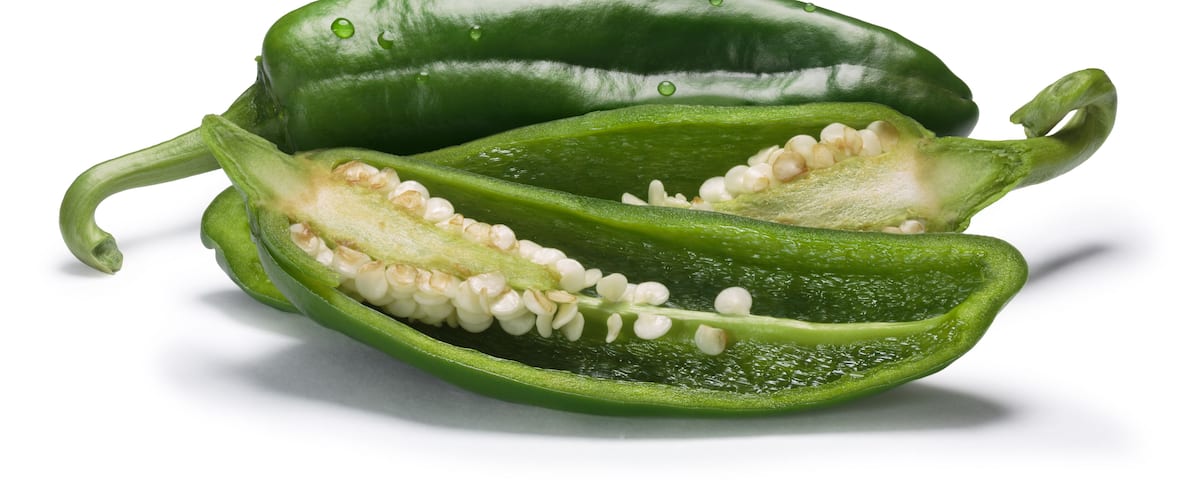 A green bell pepper cut in half, revealing its seeds and interior.
