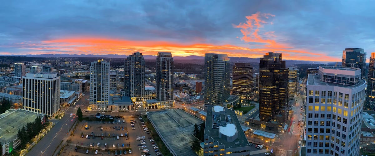 Un paisaje urbano con rascacielos, un estacionamiento y un cielo al atardecer.