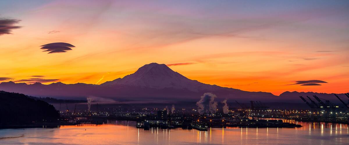 A sunset over a mountainous landscape with a city in the foreground.