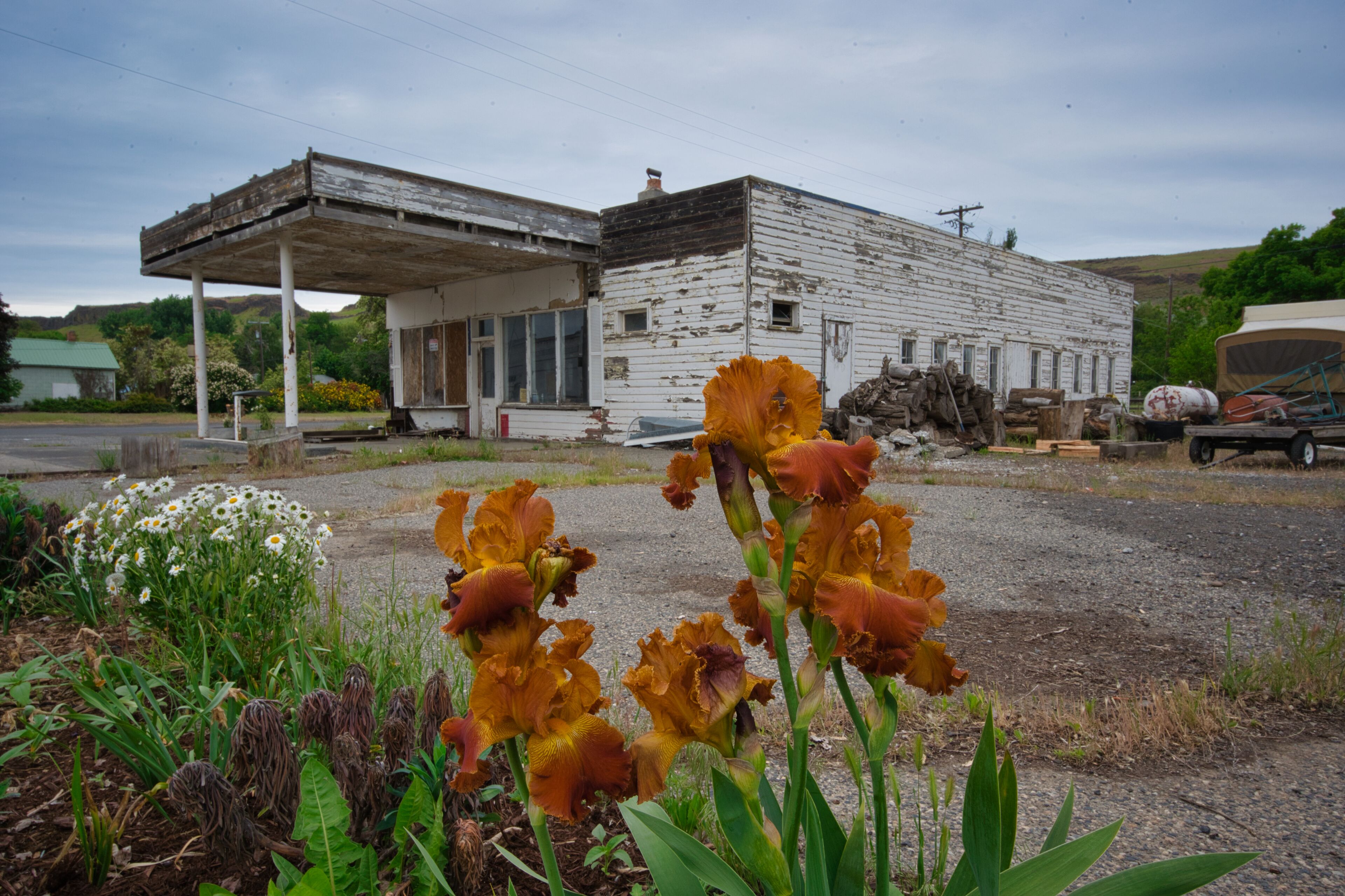 A dilapidated building with a gas station in the background.