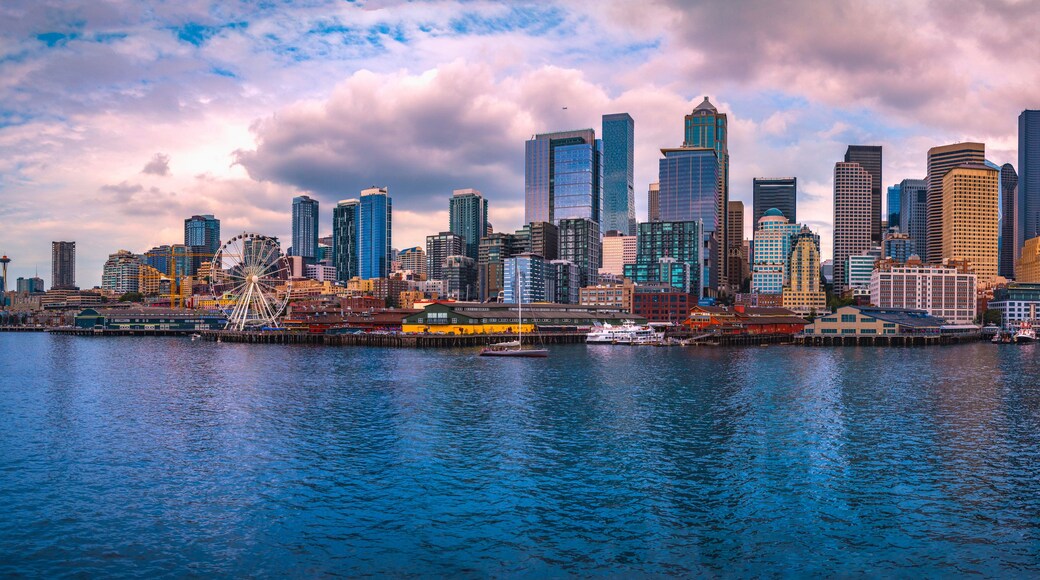 A city skyline with tall buildings and a Ferris wheel by the waterfront.