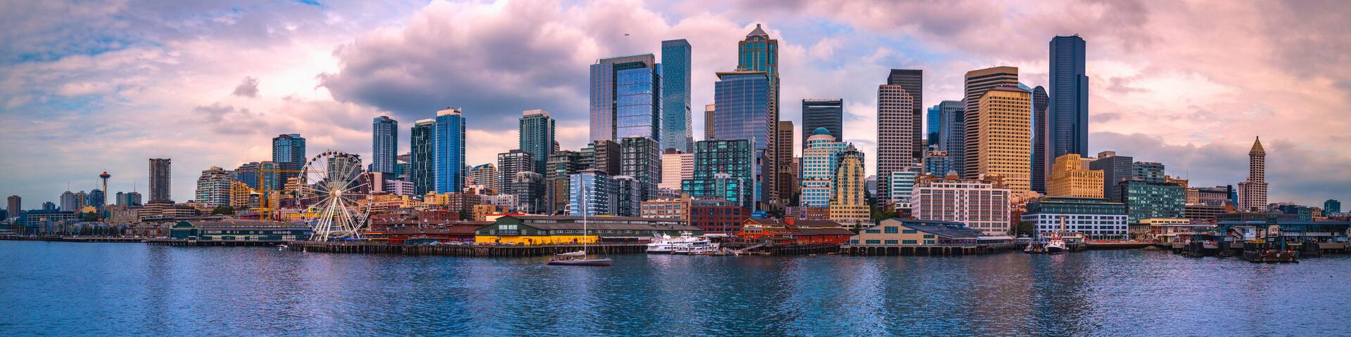 A city skyline with tall buildings and a Ferris wheel by the waterfront.