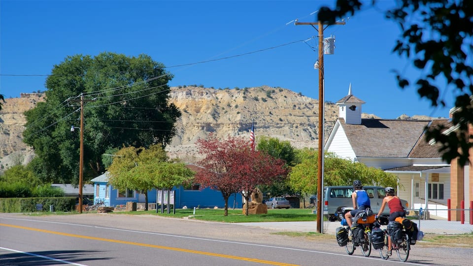 A road with cyclists, a church, and a mountain in the background.
