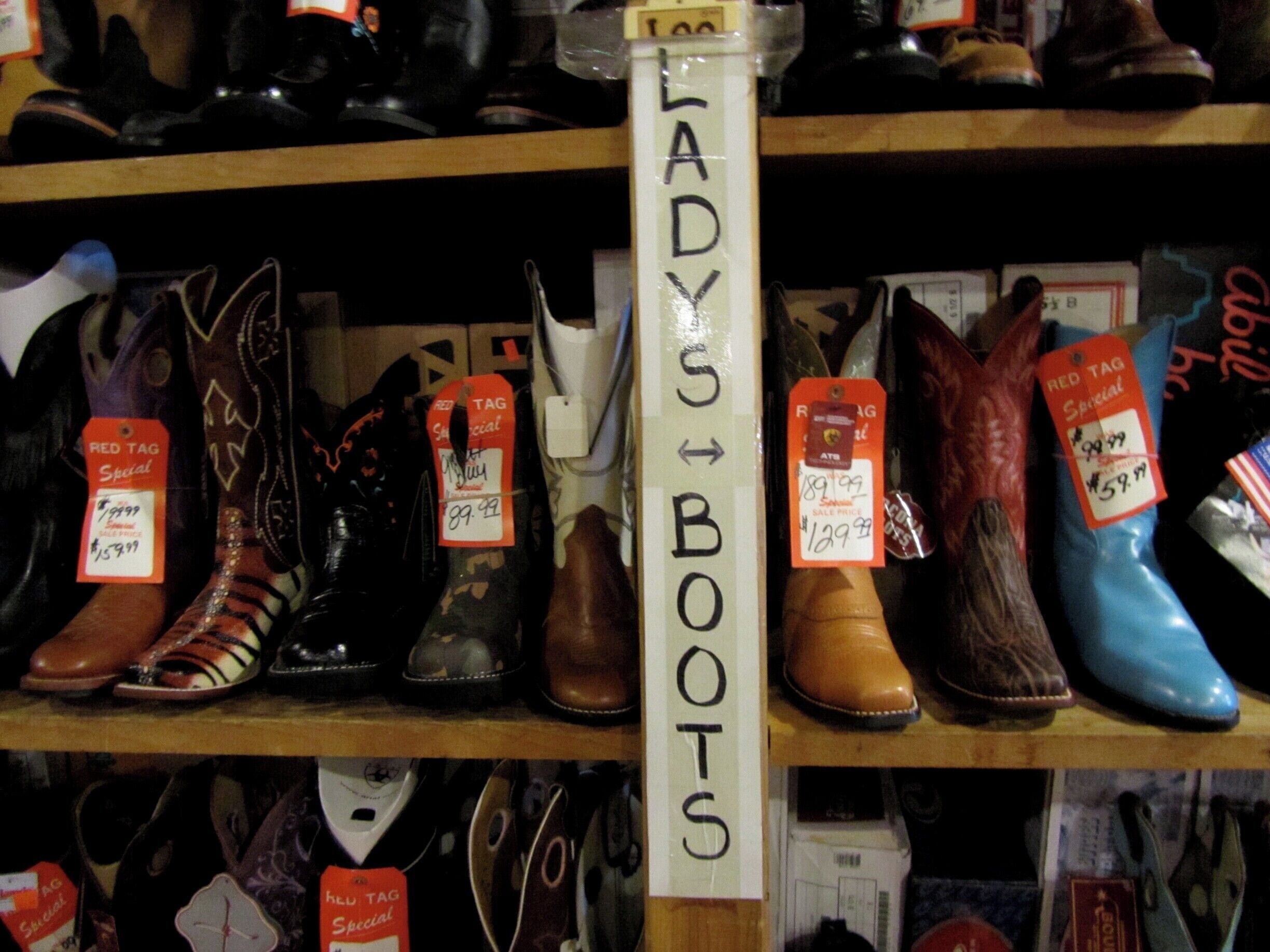 A variety of boots on shelves, with a sign indicating 'LADY BOOTS'.